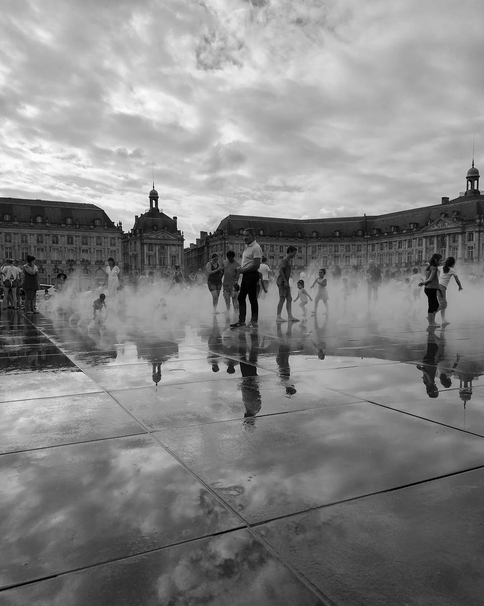 city people standing on outdoor water sprinkler park black-and-white