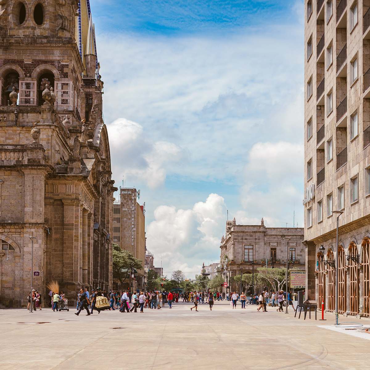 city people walking near brown ancient cathedral under white and cloudy skies town