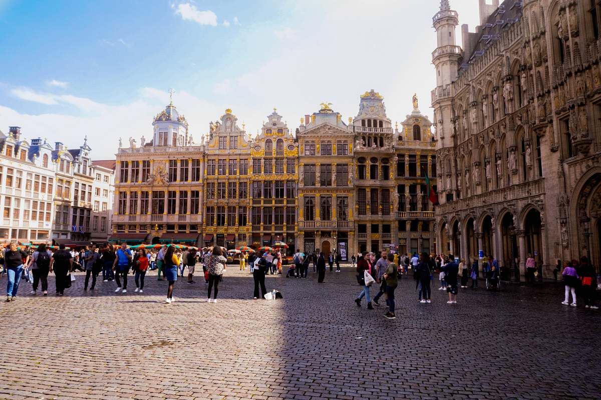 city people walking near Grand Palace, Brussels Town Hall under white and blue sky during daytime downtown