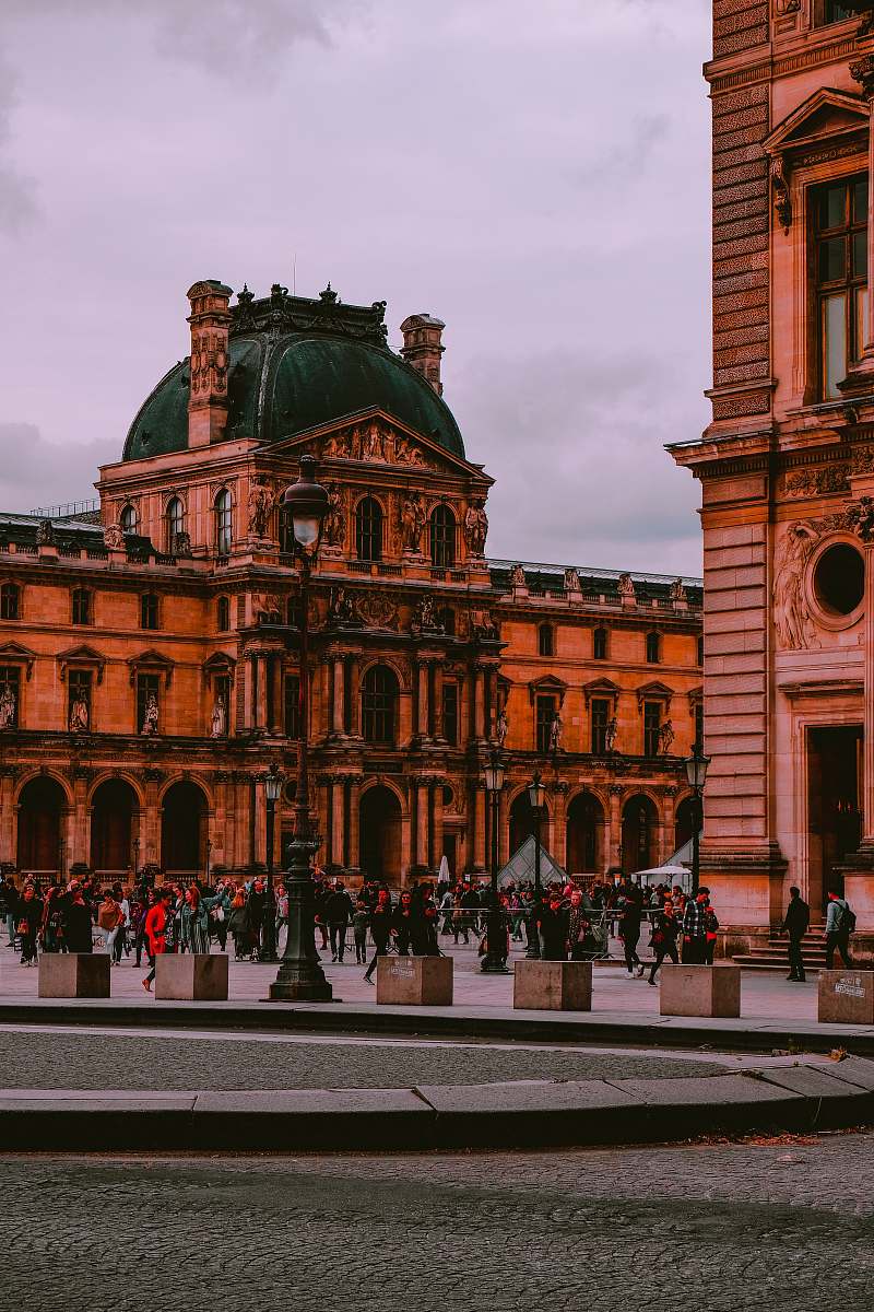city people walking near Louvre Museum in Paris, France under white skies during daytime downtown