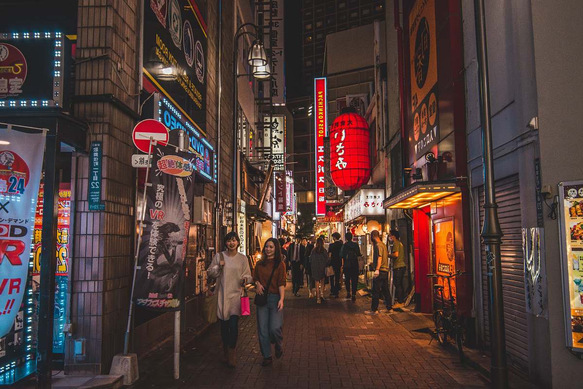 city people walking on pathway near buildings at night road
