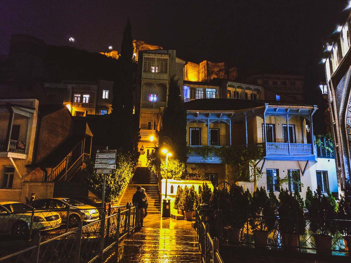 city person standing beside railings near concrete lighted houses metropolis