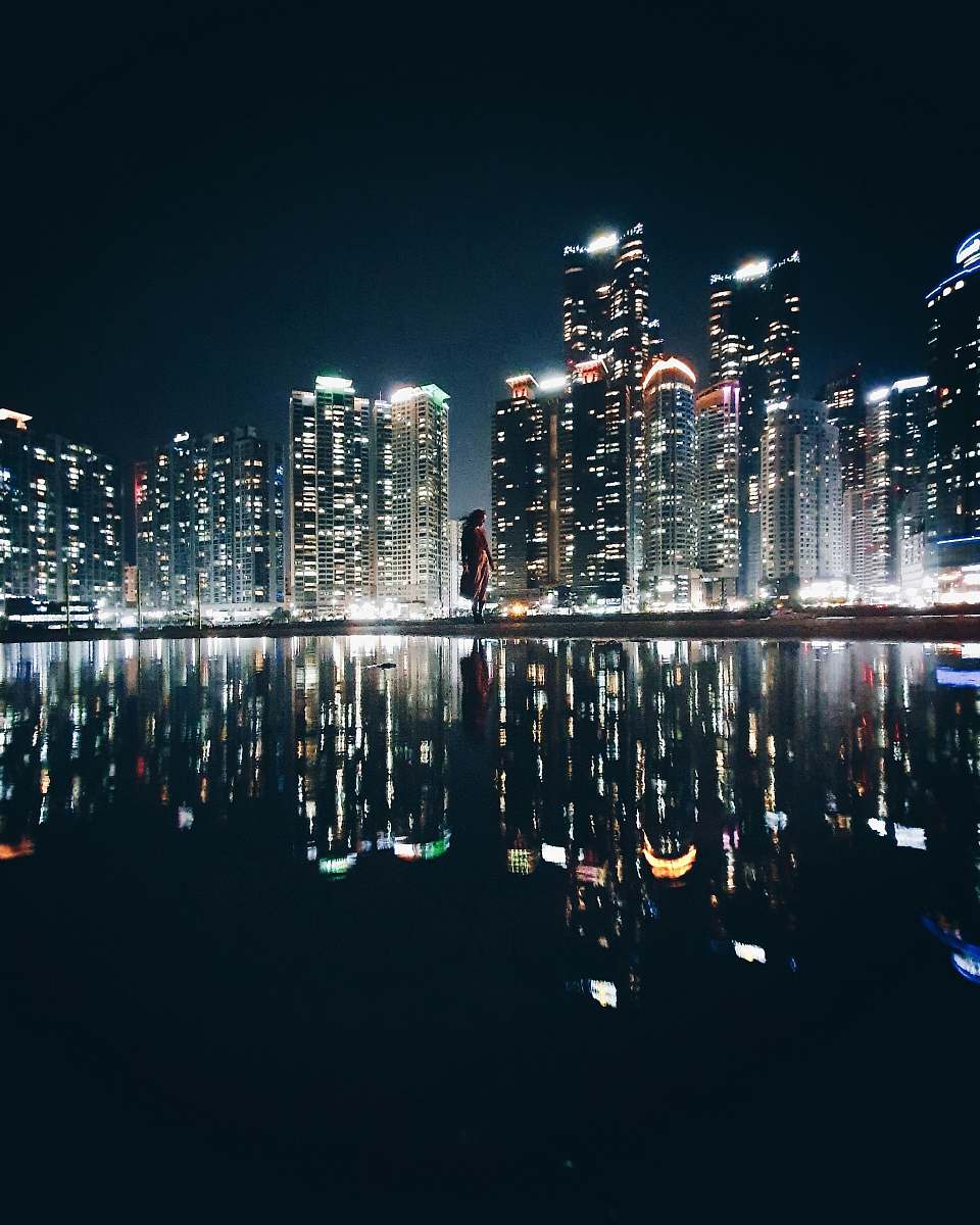 city reflection of high-rise buildings on body of water during nighttime town