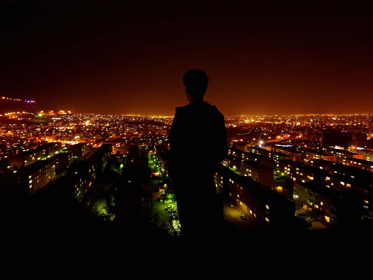 city silhouette photo of person facing on lighted city nature