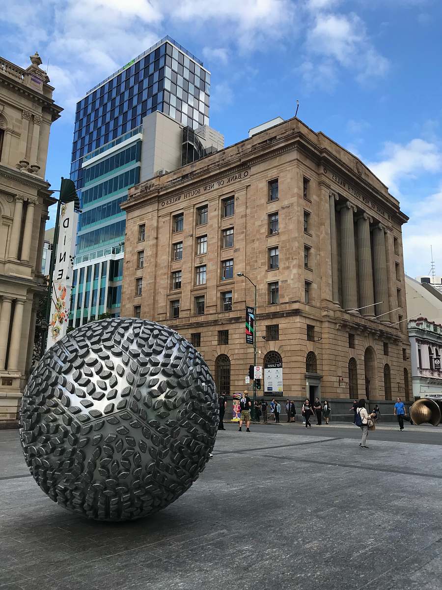 downtown silver globe statue outside a concrete building sphere