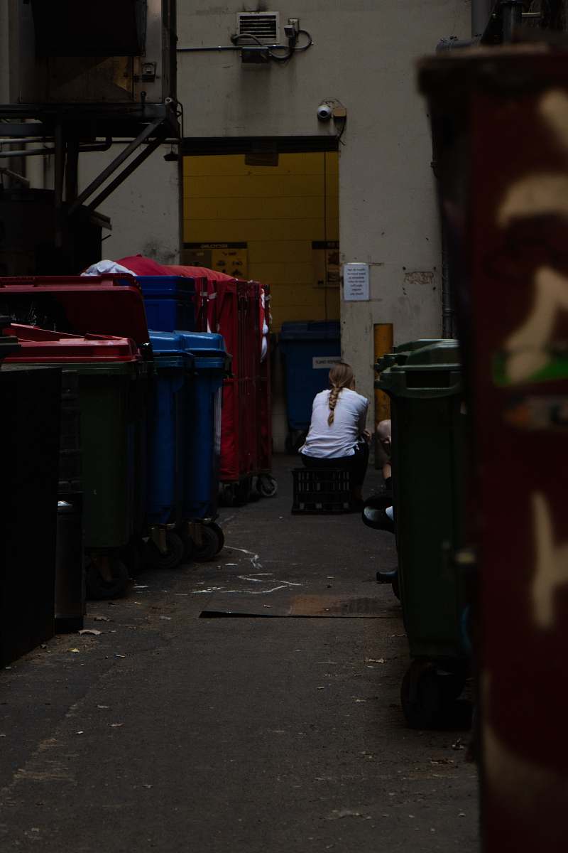 city sitting person beside container road