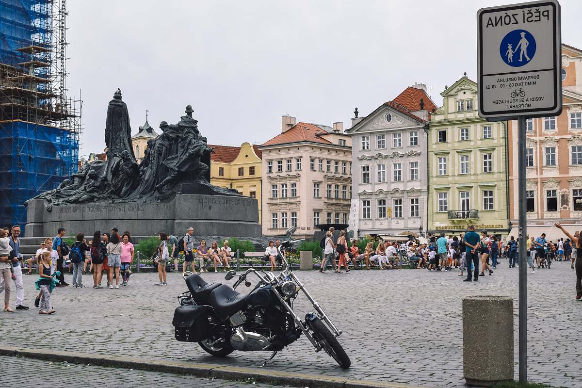 city touring motorcycle park near monument with people strolling around person