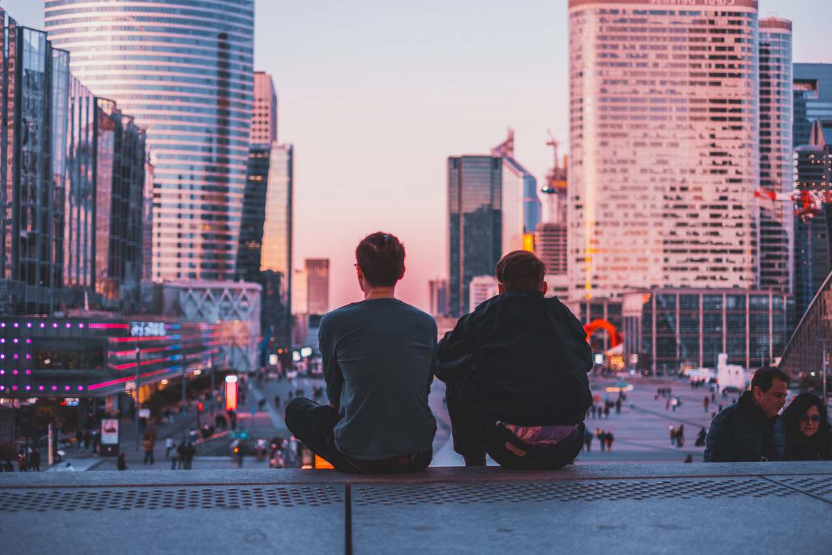 city two men sitting on stairs fronting buildings urban
