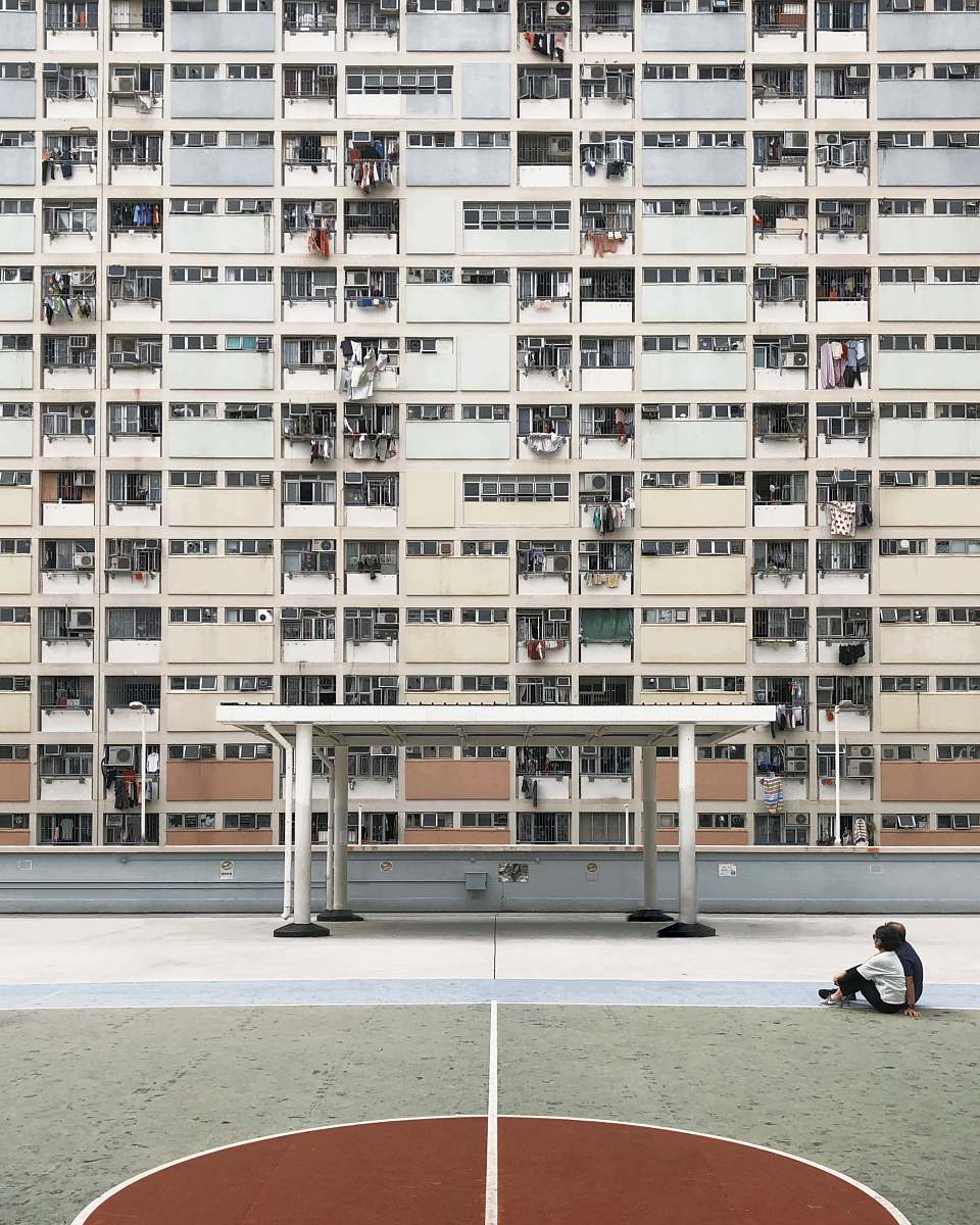 city two people sitting on concrete pavement in front of high-rise building high rise
