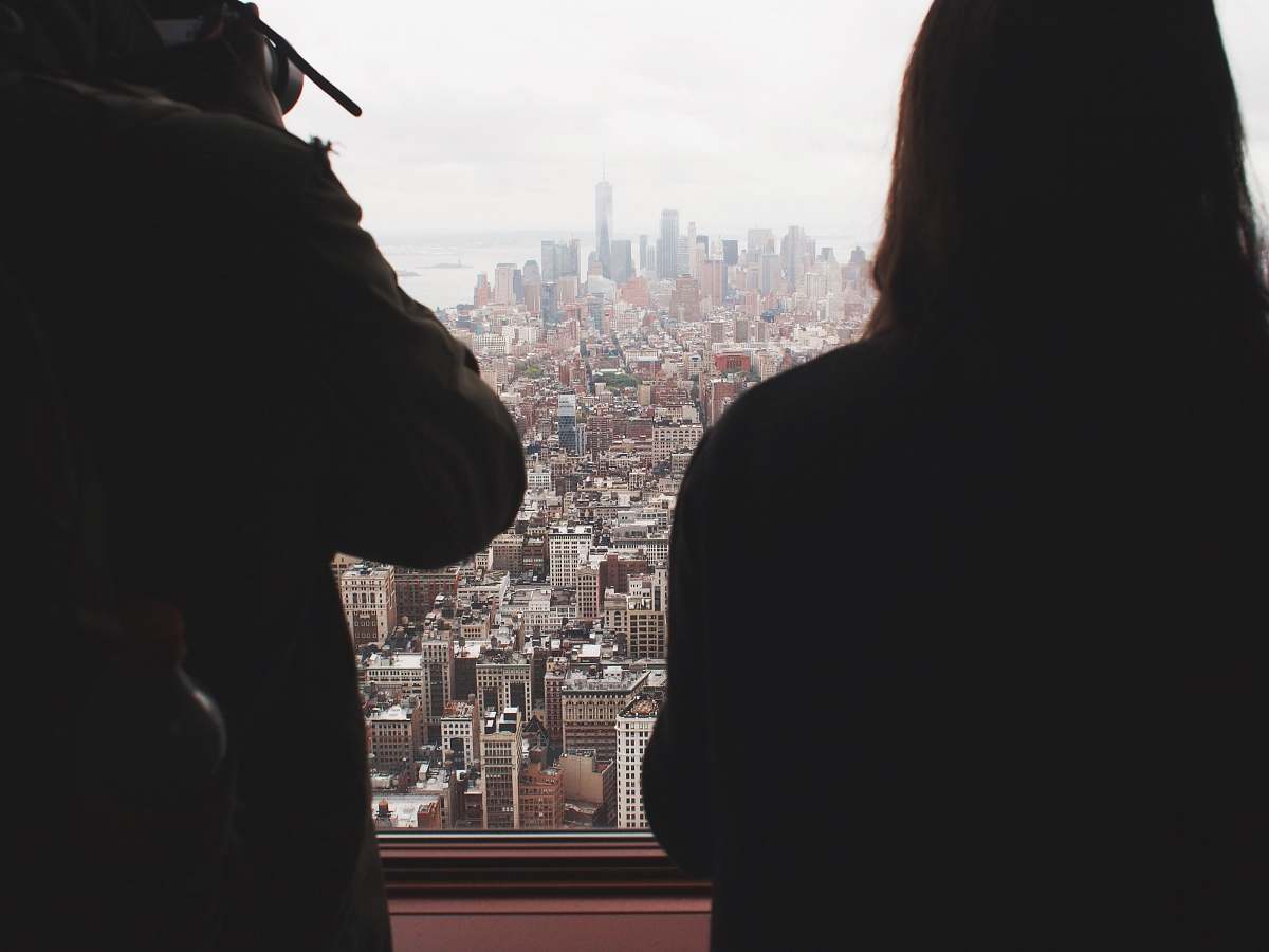 city two person standing in front of window high rise