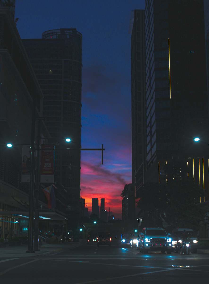 city vehicle on street between high-rise buildings during golden hour metropolis