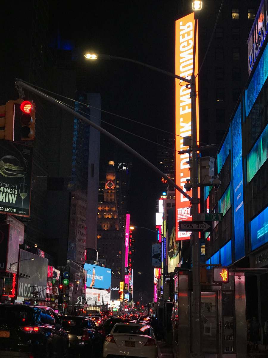 city vehicles passing between lighted buildings metropolis