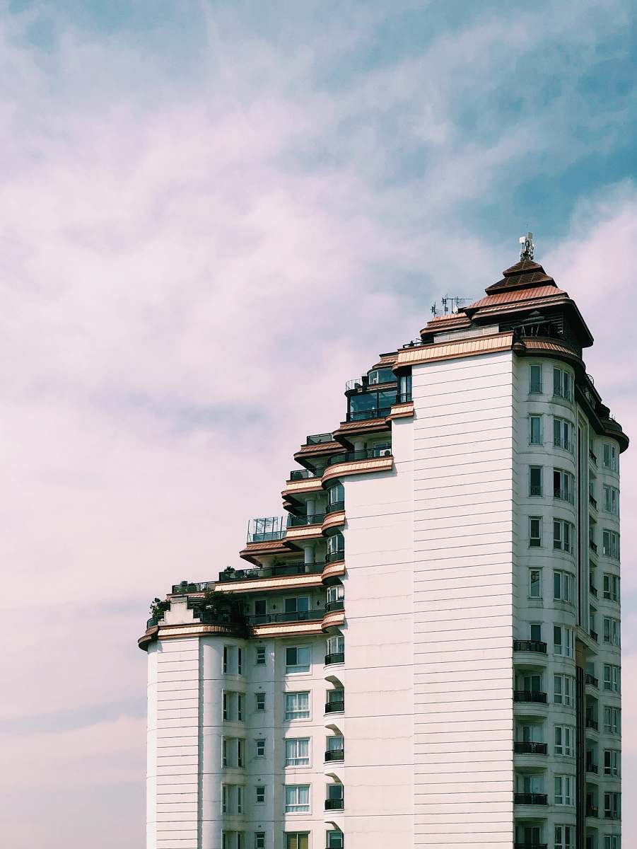 city white concrete building under cloudy sky high rise