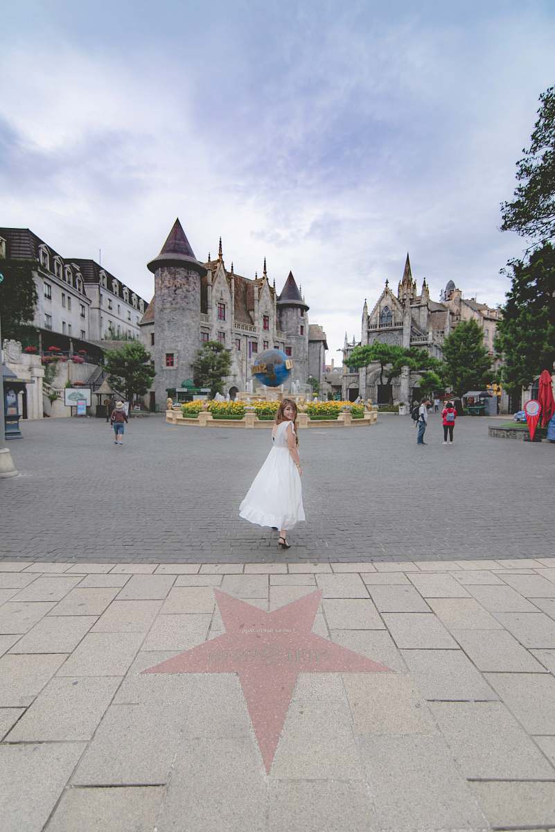 city woman in white dress standing on pavement during daytime downtown