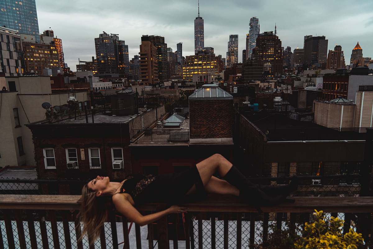 city woman lying down on a terrace overlooking city buildings metropolis