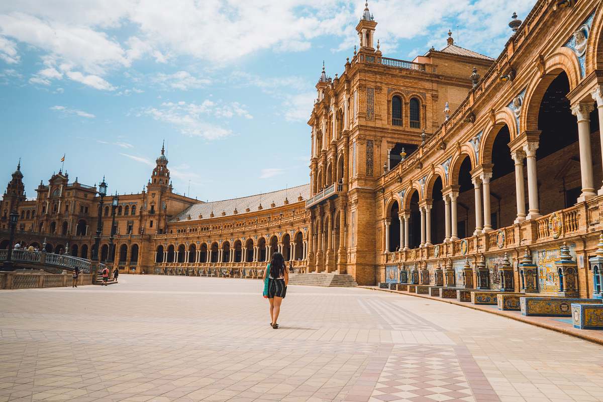 downtown woman walking near Plaza de España in Mardid under blue and white sky during daytime city