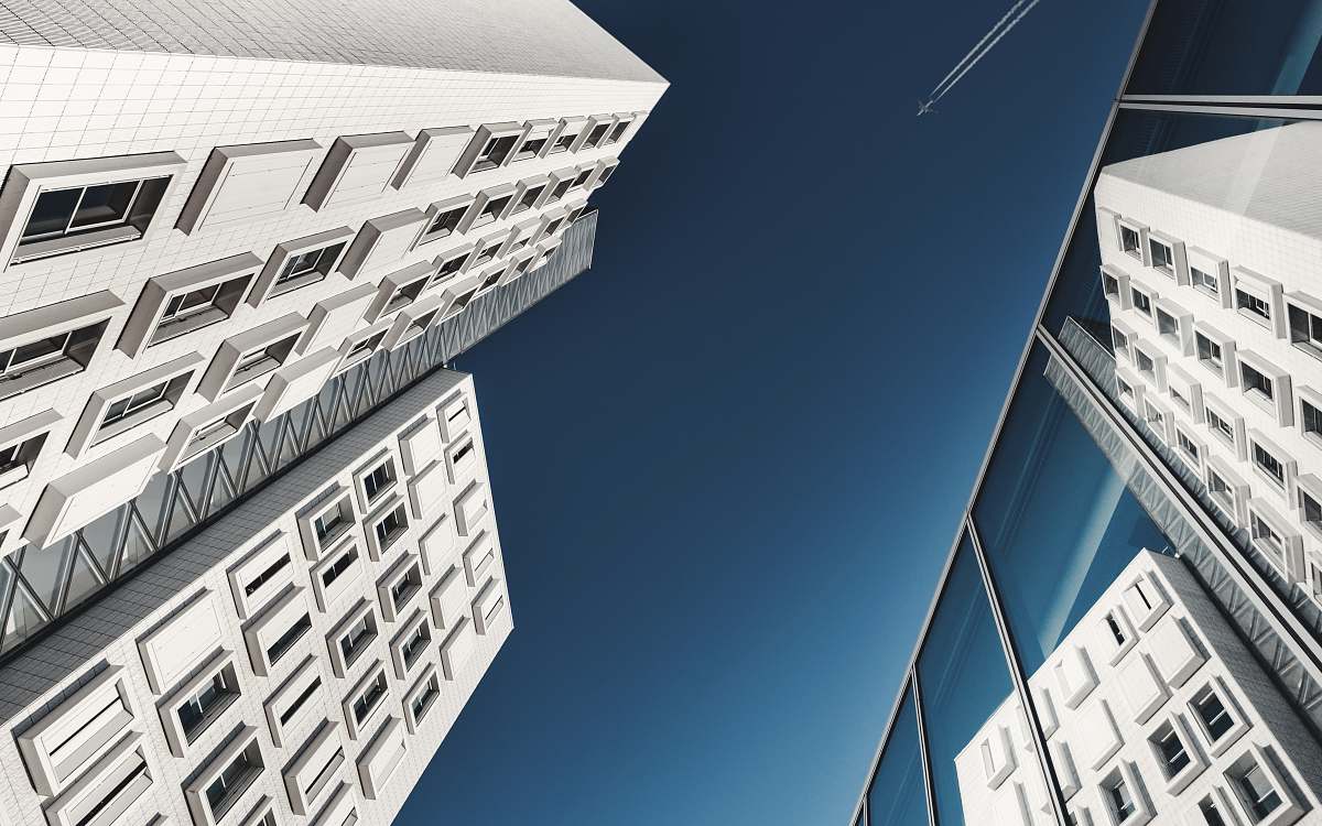 city worm's-eye view of aircraft in sky with smoke trail architecture