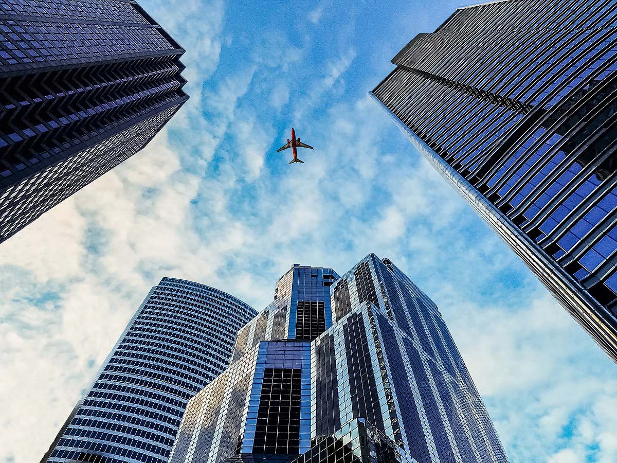 city worm's eye view of airplane passing by buildings skyscraper