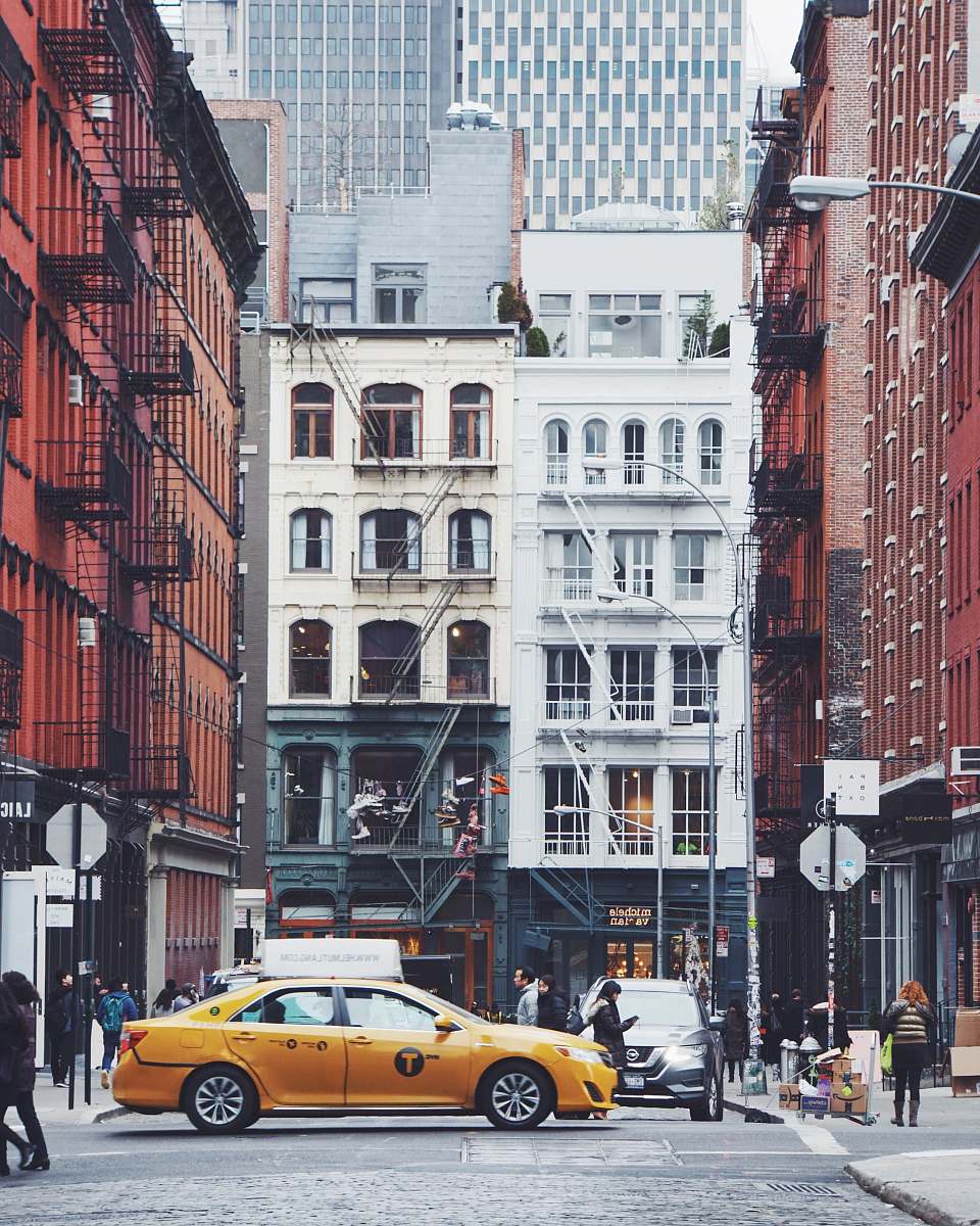 cab yellow sedan on road near buildings with people walks vehicle