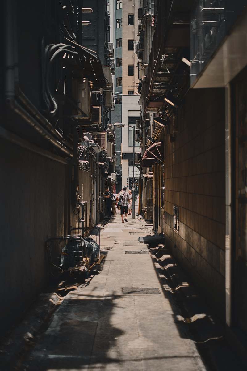 road alley photography of person walkway between building during daytime town