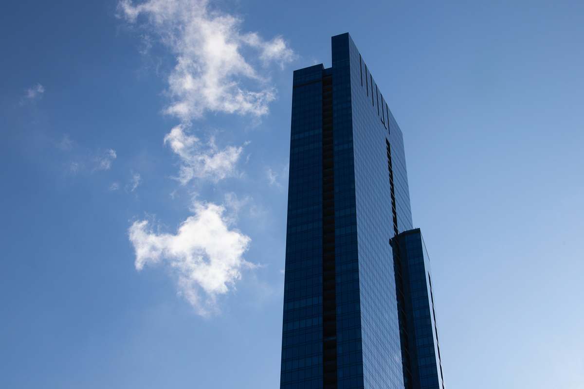 building blue glass walled high-rise building under blue and white skies high rise
