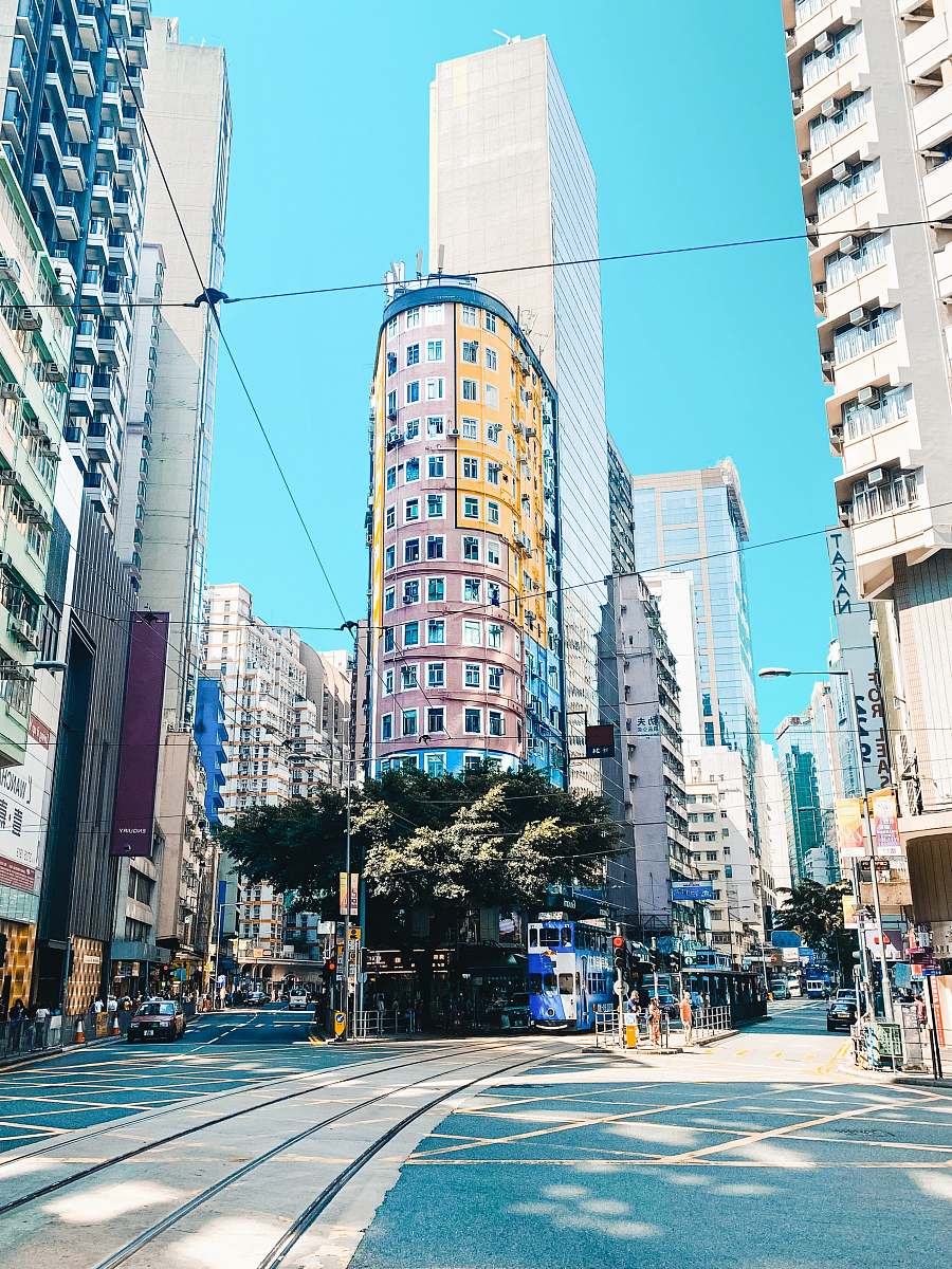Explore the dynamic essence of urban life with this captivating image of a bustling street in the heart of a modern metropolis. The scene features striking buildings that tower under a brilliant blue sky, creating a vivid contrast that embodies the energy of city living. This high-quality image is perfect for use in travel blogs, urban development presentations, or marketing materials aimed at showcasing city life.
