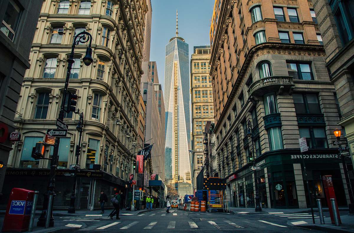 road down view of white and blue glass tower in between buildings during daytime buildings