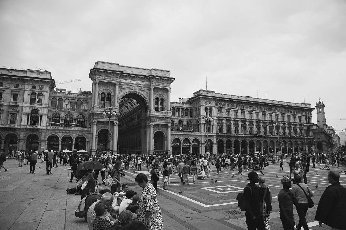 building grayscale photo of people across gray building black-and-white
