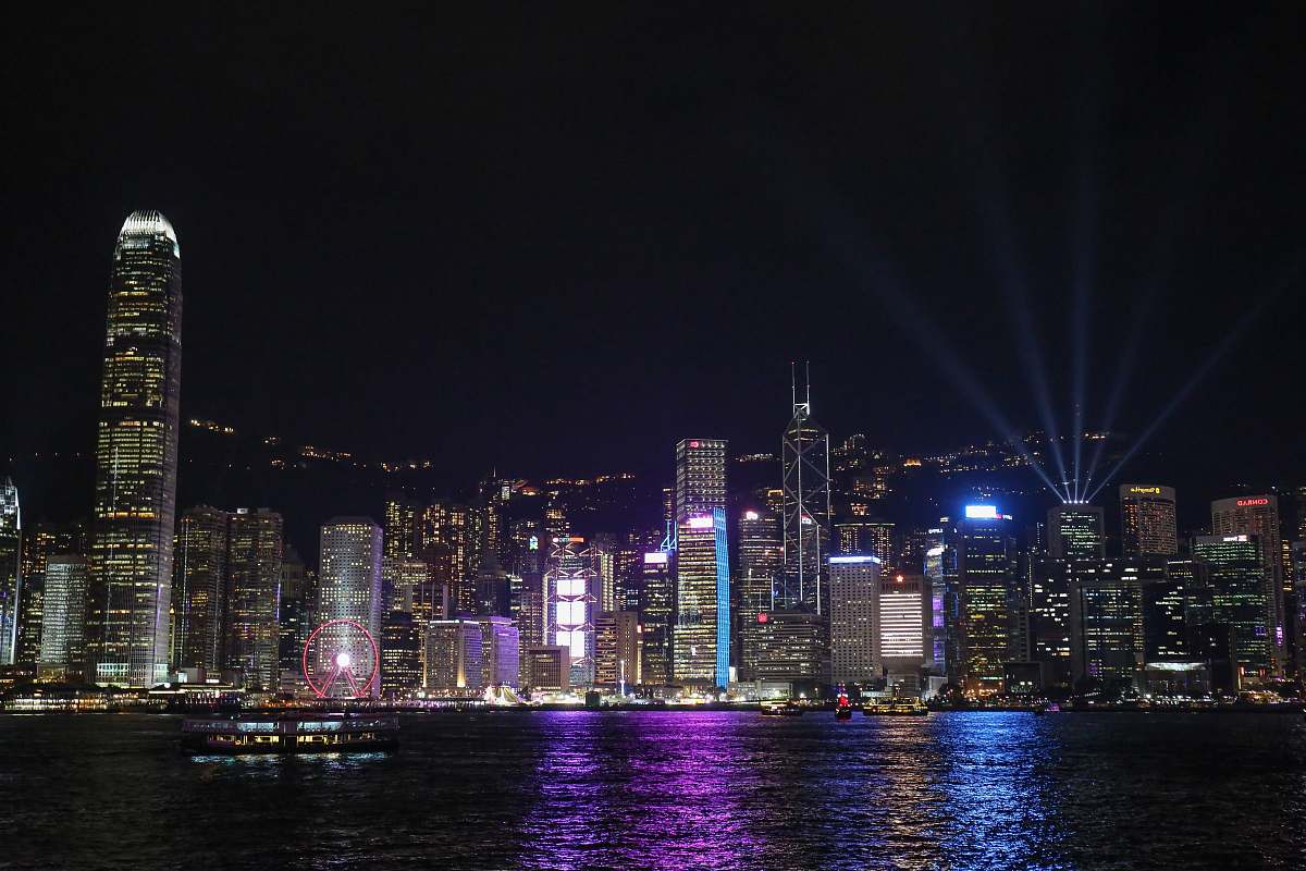building lighted city buildings near calm sea during night time metropolis