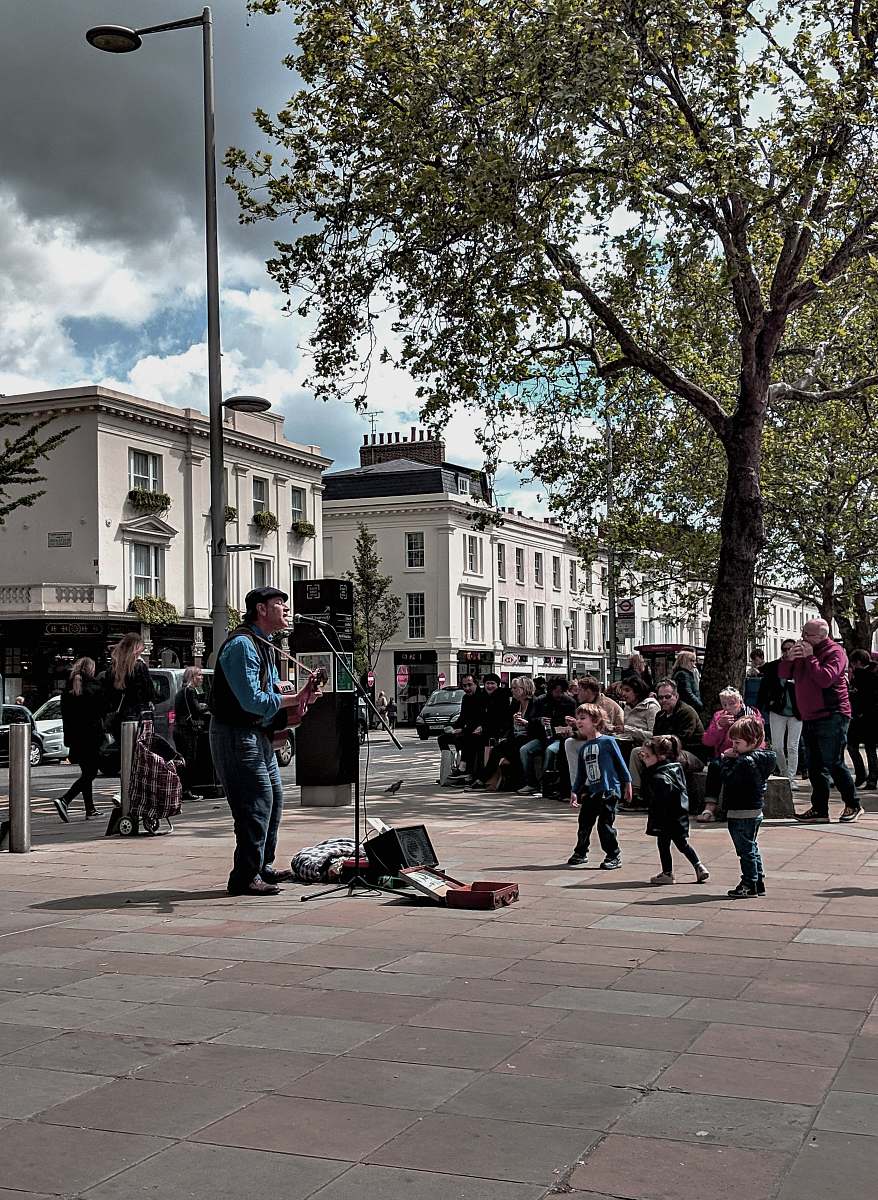 building man playing guitar surrounded with people downtown