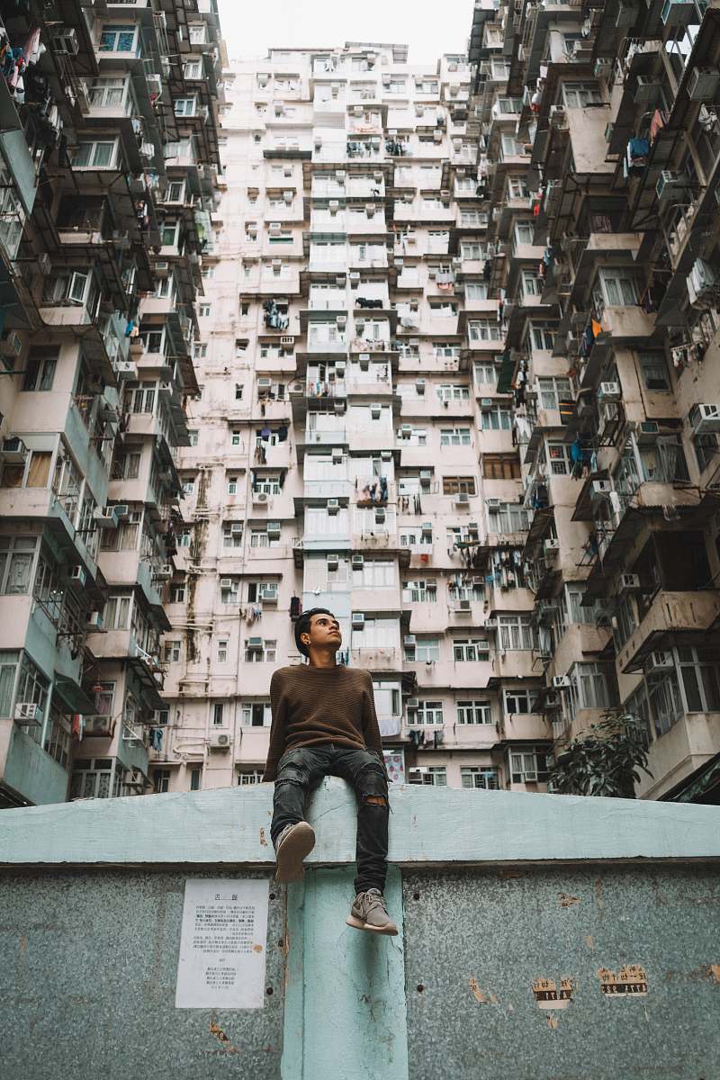 building man sitting near concrete building at daytime high rise