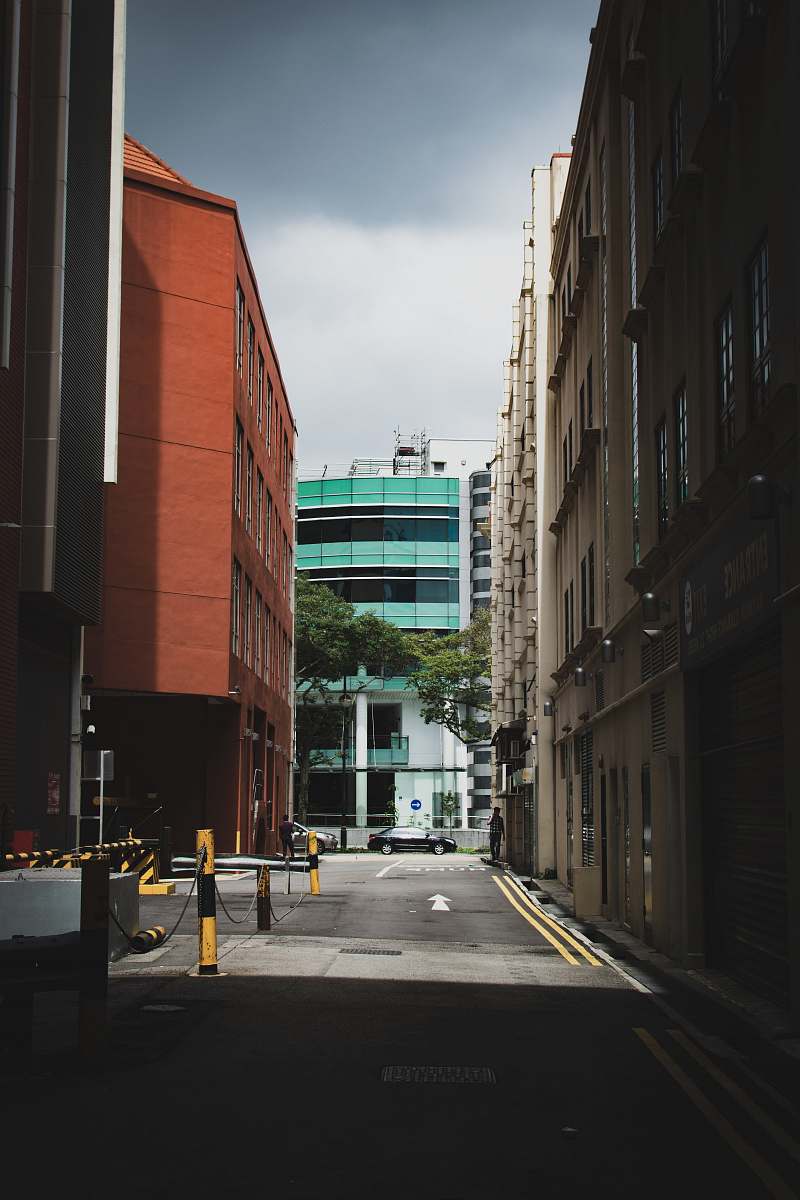 building man standing beside building near car on the road road