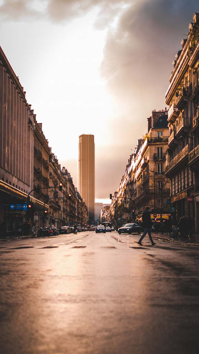 building man walks across the street road
