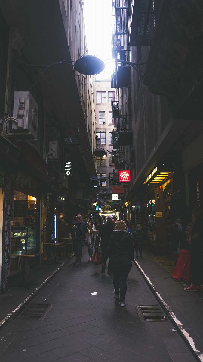 building men walking on street between buildings road