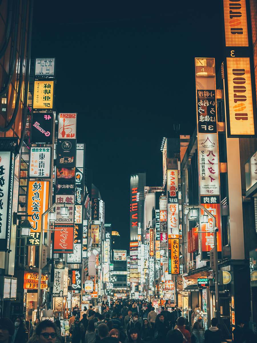 town people walking between buildings during nighttime metropolis