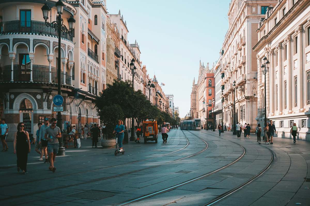urban people walking on pathway near buildings and different vehicles on road during daytime human