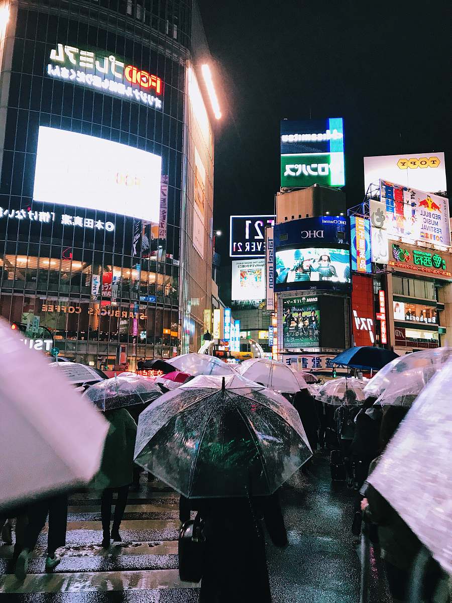 urban people with umbrellas walking near buildings during night metropolis