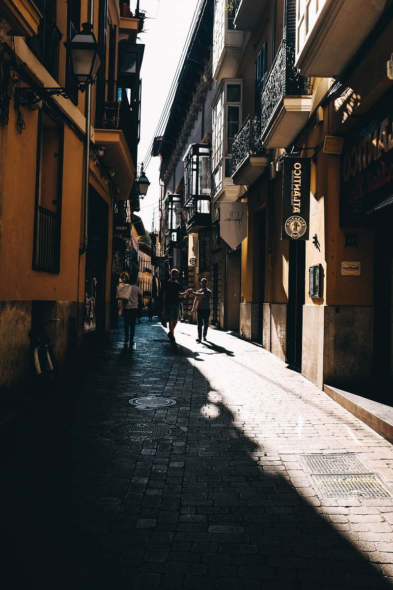 alley three person walking in between two buildings building