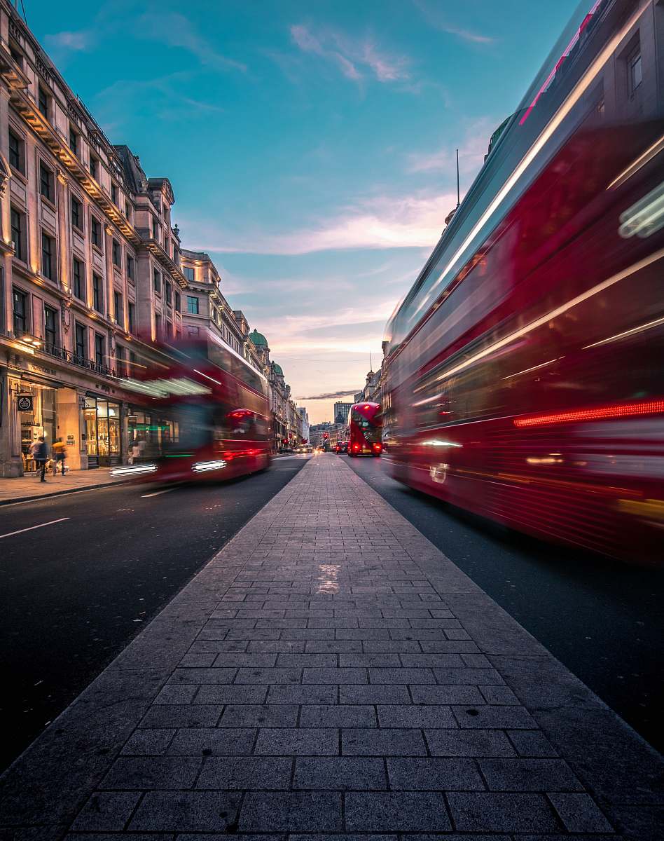 road timelapse photography of double decker bus on road between buildings london