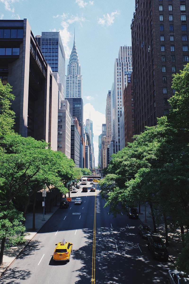 urban yellow car running on the street between the building during daytime new york