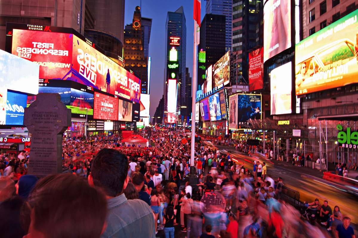 building crowd on road between buildings with electric billboards person