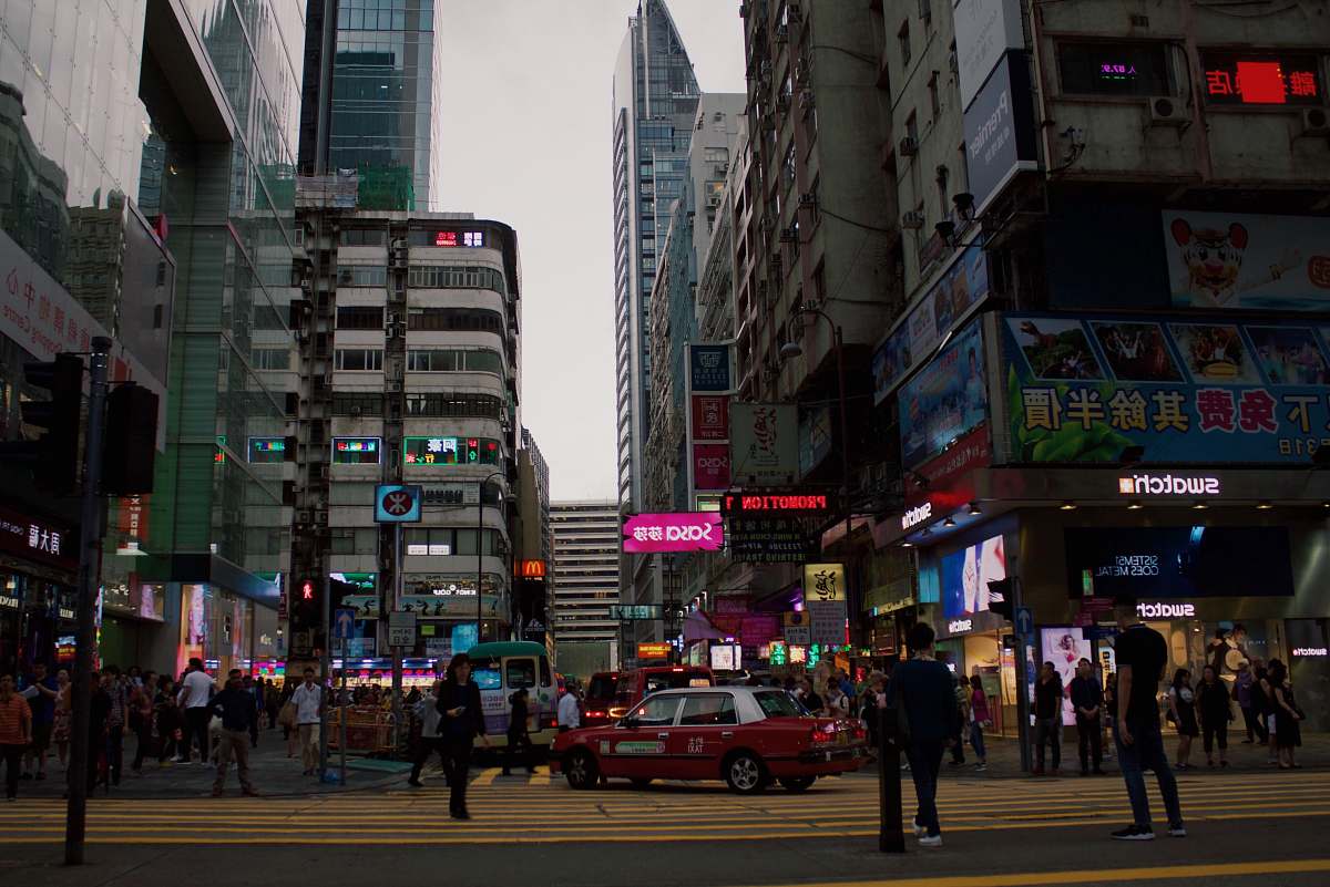 pedestrian red and white vehicle surrounded by people beside buildings person