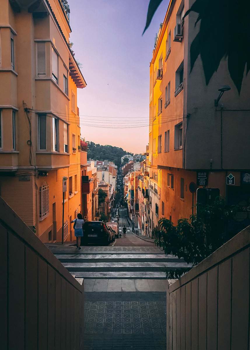 city woman in white shirt and blue skirt walking on roadside during orange sunset building