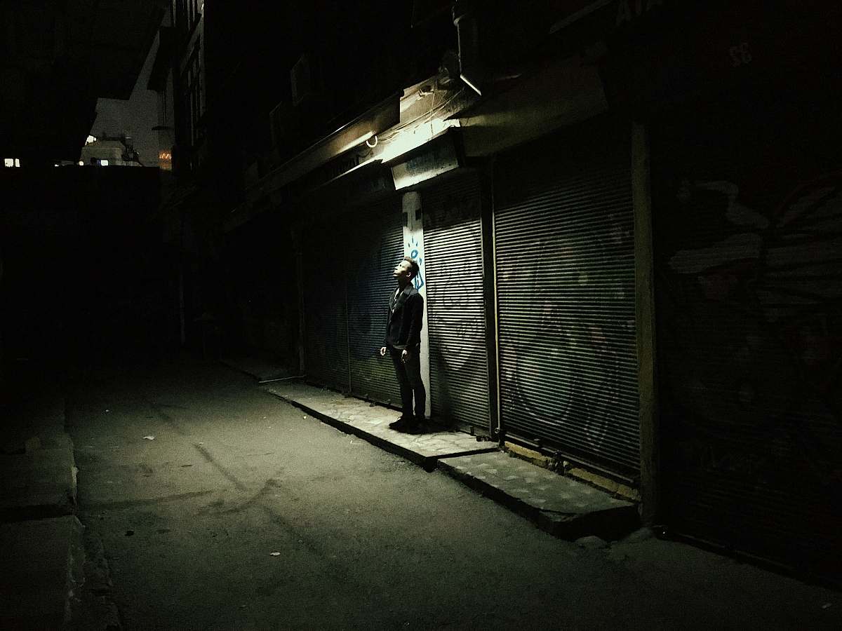 urban man standing under light during nighttime road