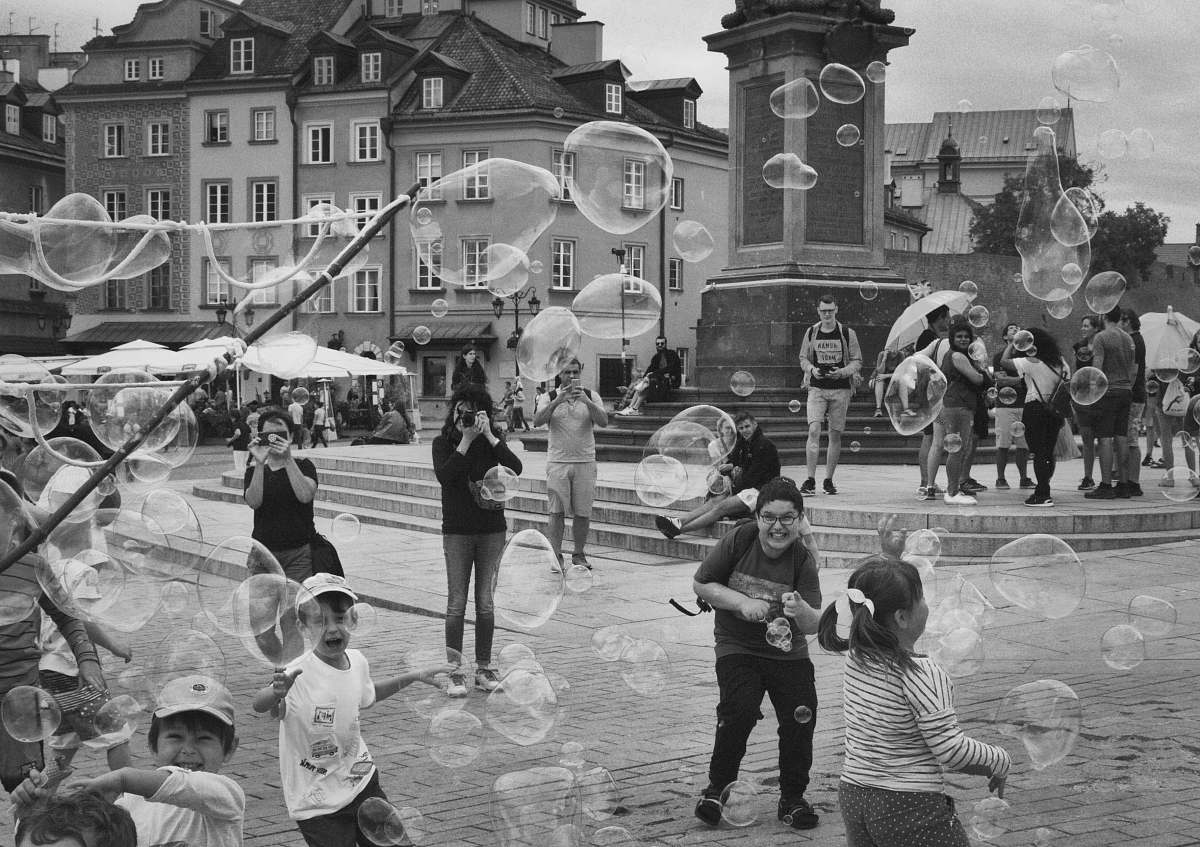 city people and children playing at the streets during day black-and-white