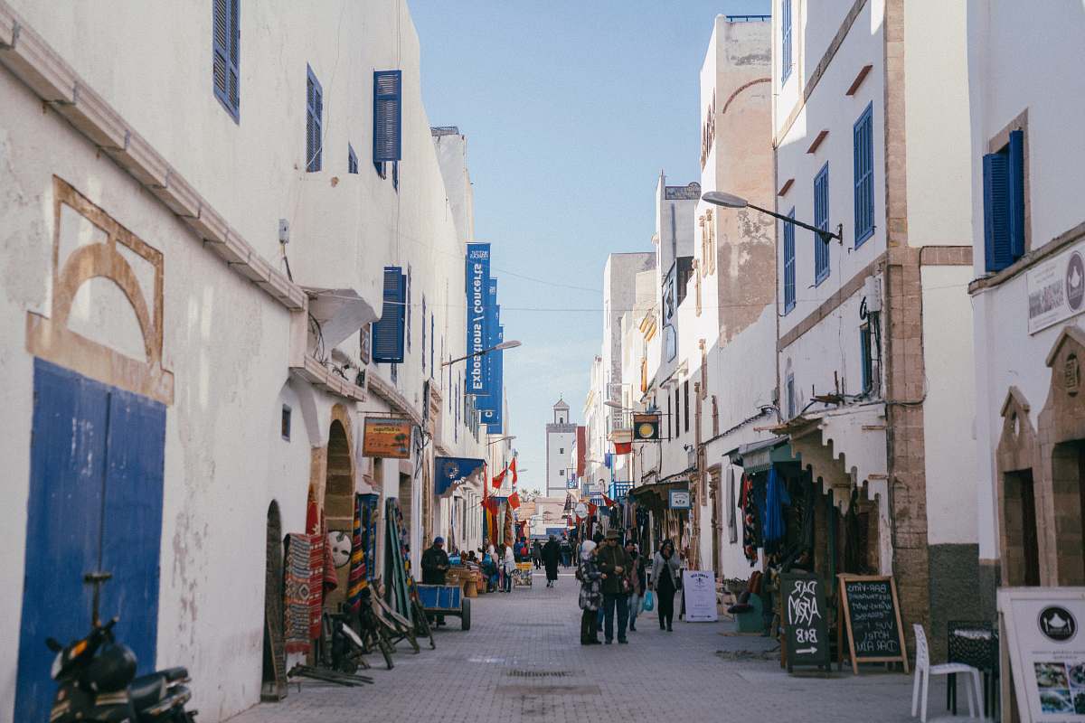 building people at alley between white-and-blue concrete buildings during daytime street