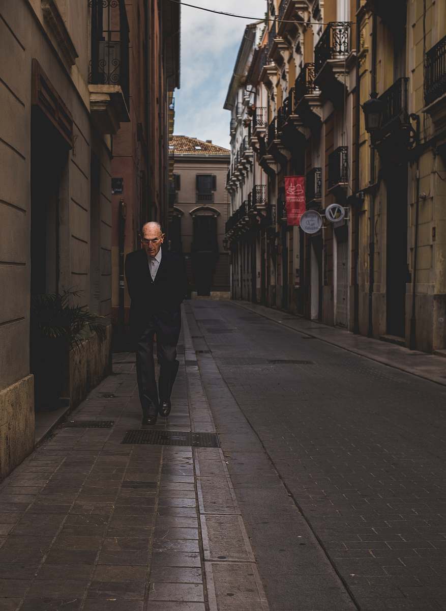 street man walking alone near road beside buildings road