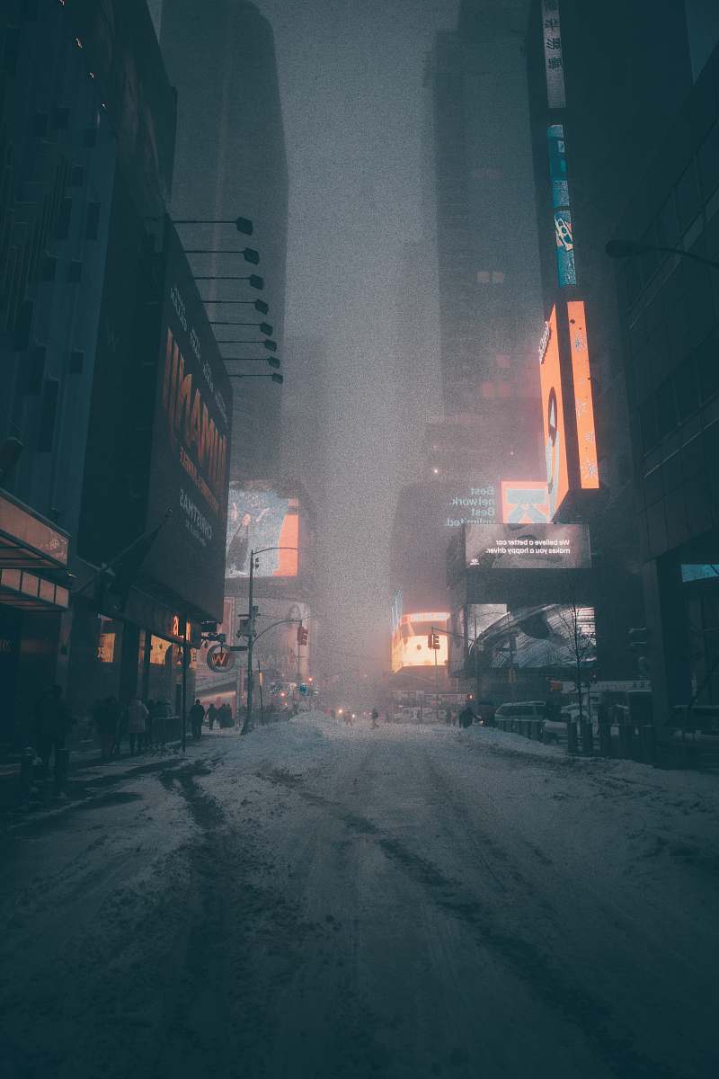 snow people walking on street surrounded by city buildings during nighttime blizzard