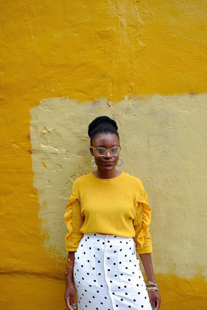 clothing woman in yellow crew neck long sleeve shirt leaning on yellow painted wall baltimore