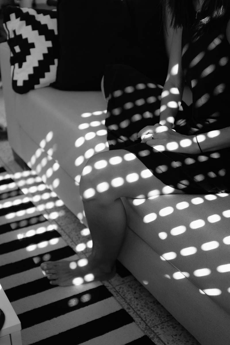 black-and-white grayscale photography of barefooted person sitting on couch lighting
